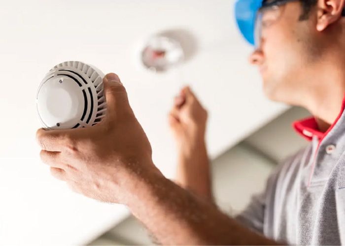 Kỹ thuật viên TMK đang trực tiếp lắp đặt và kiểm tra đầu báo cháy trên trần nhà cho dự án doanh nghiệp.